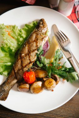 Izgara balık patates, domates, salata yaprağı, limon parça ve maydanoz ile