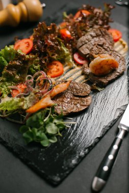 Izgara sığır eti taze sebze ve salata ile servis kara tahta üzerinde yapraklar