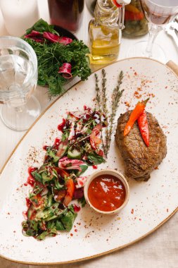 kaburga eti beyaz tabakta salata ve domates soslu