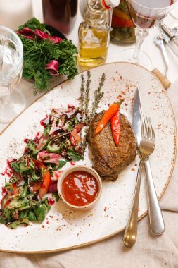 kaburga eti beyaz tabakta salata ve domates soslu