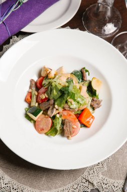 Beyaz tabakta et ve sosis ile sebze güveç