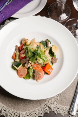 Beyaz tabakta et ve sosis ile sebze güveç