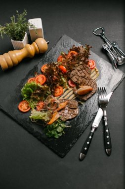 Izgara sığır eti taze sebze ve salata ile servis kara tahta üzerinde yapraklar