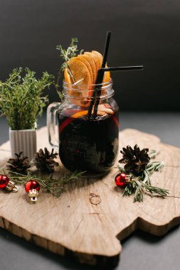 Portakal dilimleri, payet, Noel topları, çam kozalakları ve biberiye şube ile dekore edilmiş şenlikli mulled şarap sawed tahtaya hizmet