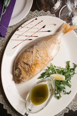 Lezzetli dorada roka ve beyaz tabakta tropikal sos ile servis