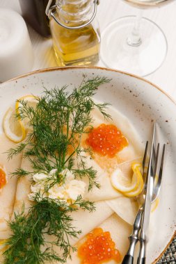 Krep kırmızı havyar, yağ, limon ve dereotu ile tabakta 