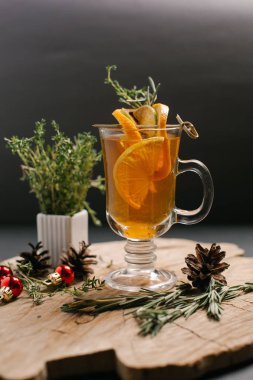 Portakal, limon dilimleri ve Noel topları, çam kozalakları ve biberiye şube ile dekore edilmiş bal da dahil olmak üzere şenlikli içecek sawed tahtaya hizmet