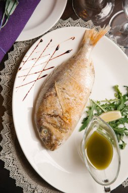 Lezzetli dorada roka ve beyaz tabakta tropikal sos ile servis