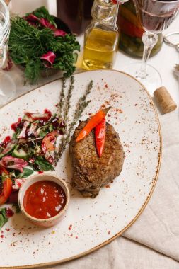 kaburga eti beyaz tabakta salata ve domates soslu