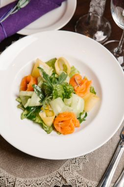 Beyaz tabakta kabak dilimleri, somon, roka ve peynir salatası