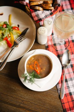 Et çorbası servis beyaz çorba kasesi dolmalık biber dilimleri, arka plan üzerinde salata ile