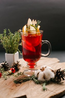 Kızılcık, limon, limon dilimleri ve Noel topları, çam kozalakları ve biberiye şube ile dekore edilmiş bal da dahil olmak üzere şenlikli tatlı içecek sawed tahtaya hizmet
