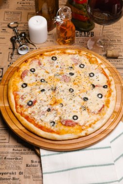 Ahşap tepsi peynirli pizza salam, zeytin ve otlar ile hizmet