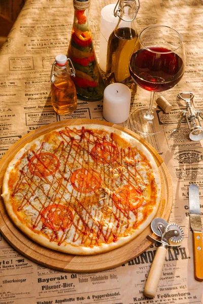 Chicken pizza with mozzarella, tomatoes and ketchup on top served on wooden board