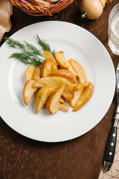 fried potato slices served on white plate with dill