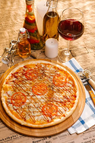 Chicken pizza with mozzarella, tomatoes and ketchup on top served on wooden board