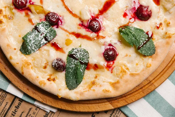 Sweet pizza with mozzarella, cherry and mint leaves