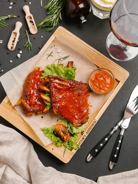 Grilled glazed ribs with tabasco sauce on wooden tray with herbs