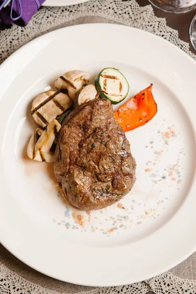 Grilled beef with mushrooms, zucchini and pepper served on white plate