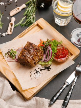 Kaburga eti sebze ve ahşap tepsi üzerinde domates sosu ile