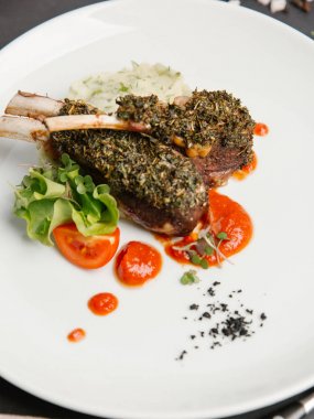 pirzola bitkisel sosu altında beyaz tabakta domates sosu ile servis ezme patates ile