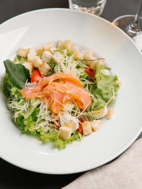 Beyaz tabakta yeşil salata somon ve kruton serpin Parmesan ile