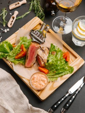 Dilimlenmiş yeşil yaprakları, hardal ahşap tepsi ve domates ile servis kaburga eti