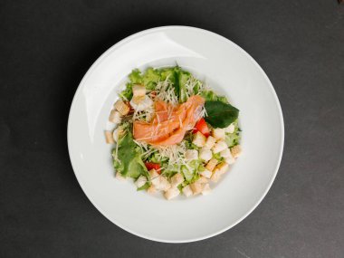 Beyaz tabakta yeşil salata somon ve kruton serpin Parmesan ile