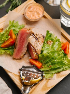 Dilimlenmiş yeşil yaprakları, hardal ahşap tepsi ve domates ile servis kaburga eti