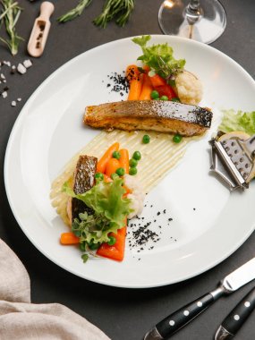 Bebek havuç, yeşil yaprakları ve limon dilimi ile kavrulmuş beyaz balık biftek servis