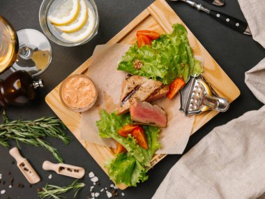 Dilimlenmiş yeşil yaprakları, hardal ahşap tepsi ve domates ile servis kaburga eti