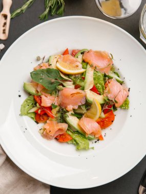 Tuzlanmış somon ve beyaz tabakta sebze salatası