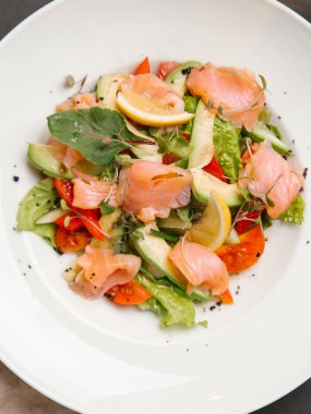 Tuzlanmış somon ve beyaz tabakta sebze salatası