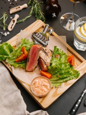 Dilimlenmiş yeşil yaprakları, hardal ahşap tepsi ve domates ile servis kaburga eti