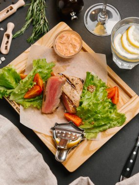 Dilimlenmiş yeşil yaprakları, hardal ahşap tepsi ve domates ile servis kaburga eti