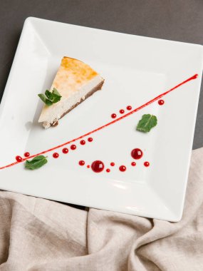 Peynirli kek çikolata temel üzerinde kızılcık sosu ile servis ve kare plaka üzerine nane yaprakları