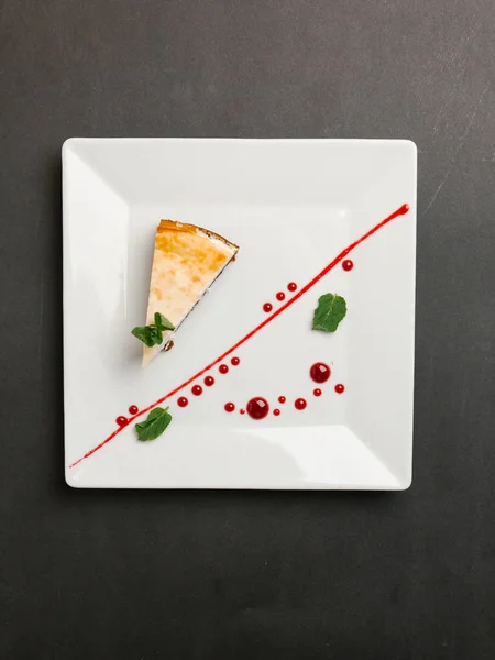 クランベリー ソース添えチョコレート ベースのチーズケーキと正方形平板のミントの葉 — ストック写真