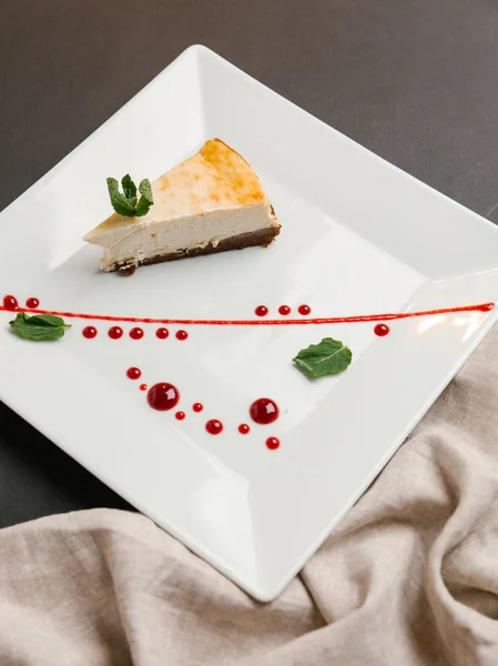 クランベリー ソース添えチョコレート ベースのチーズケーキと正方形平板のミントの葉 — ストック写真