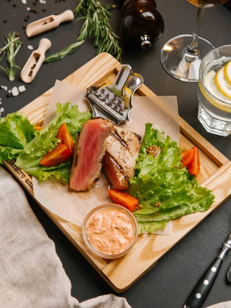 Dilimlenmiş yeşil yaprakları, hardal ahşap tepsi ve domates ile servis kaburga eti