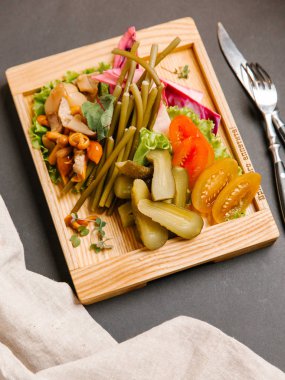 Chaser turşu çeşitleri ile ahşap tepsi üzerinde taze sebze ile servis