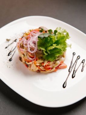 Beyaz tabakta sebze salatası mayonez sos ve üstte doğranmış soğan