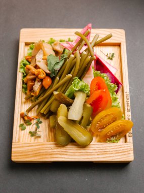 Chaser turşu çeşitleri ile ahşap tepsi üzerinde taze sebze ile servis