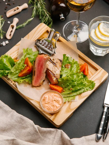 Dilimlenmiş yeşil yaprakları, hardal ahşap tepsi ve domates ile servis kaburga eti