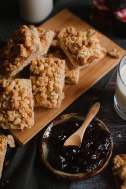 Doğrama kurulu üzerinde süt ve meyve reçeli ile rendelenmiş pasta servis