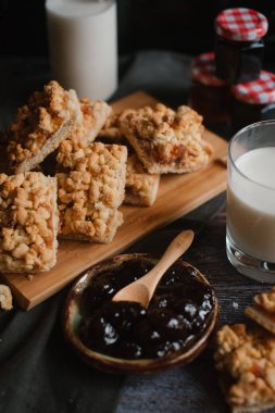 Doğrama kurulu üzerinde süt ve meyve reçeli ile rendelenmiş pasta servis