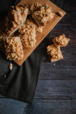 Ahşap doğrama tahtası ve koyu gri peçete üzerinde Görünümü Kapat rendelenmiş pasta servis