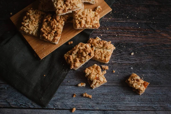 Hizmet üzerinde Ahşap doğrama tahtası ve karanlık peçete içinde elma reçel ile rendelenmiş pastadan Üstten Görünüm