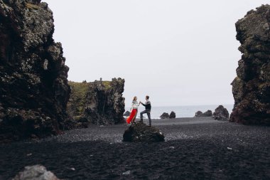 Kayanın üzerinde duran ve el ele tutuşarak genç Çift