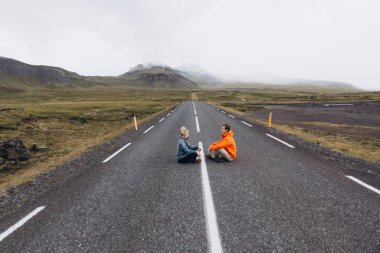 Yolun birbirlerine önünde oturan genç çift yan görünüm