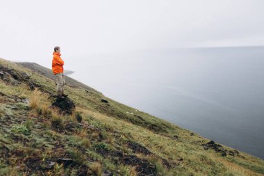 Tepede duran ve doğal manzarayı genç adam
